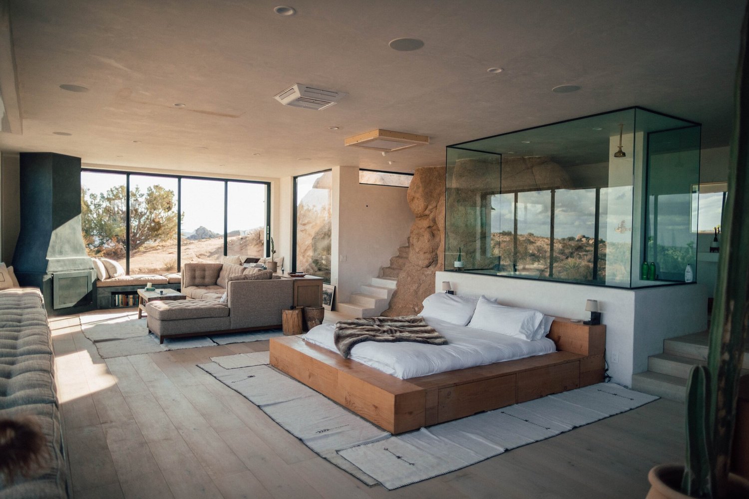 Modern suite with a low platform bed and glass-walled bathroom opening onto a terrace