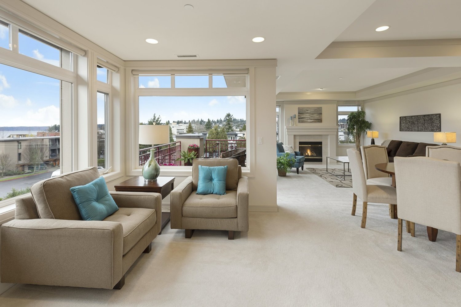 Bright extended-stay living room with sofas, fireplace and floor-to-ceiling windows